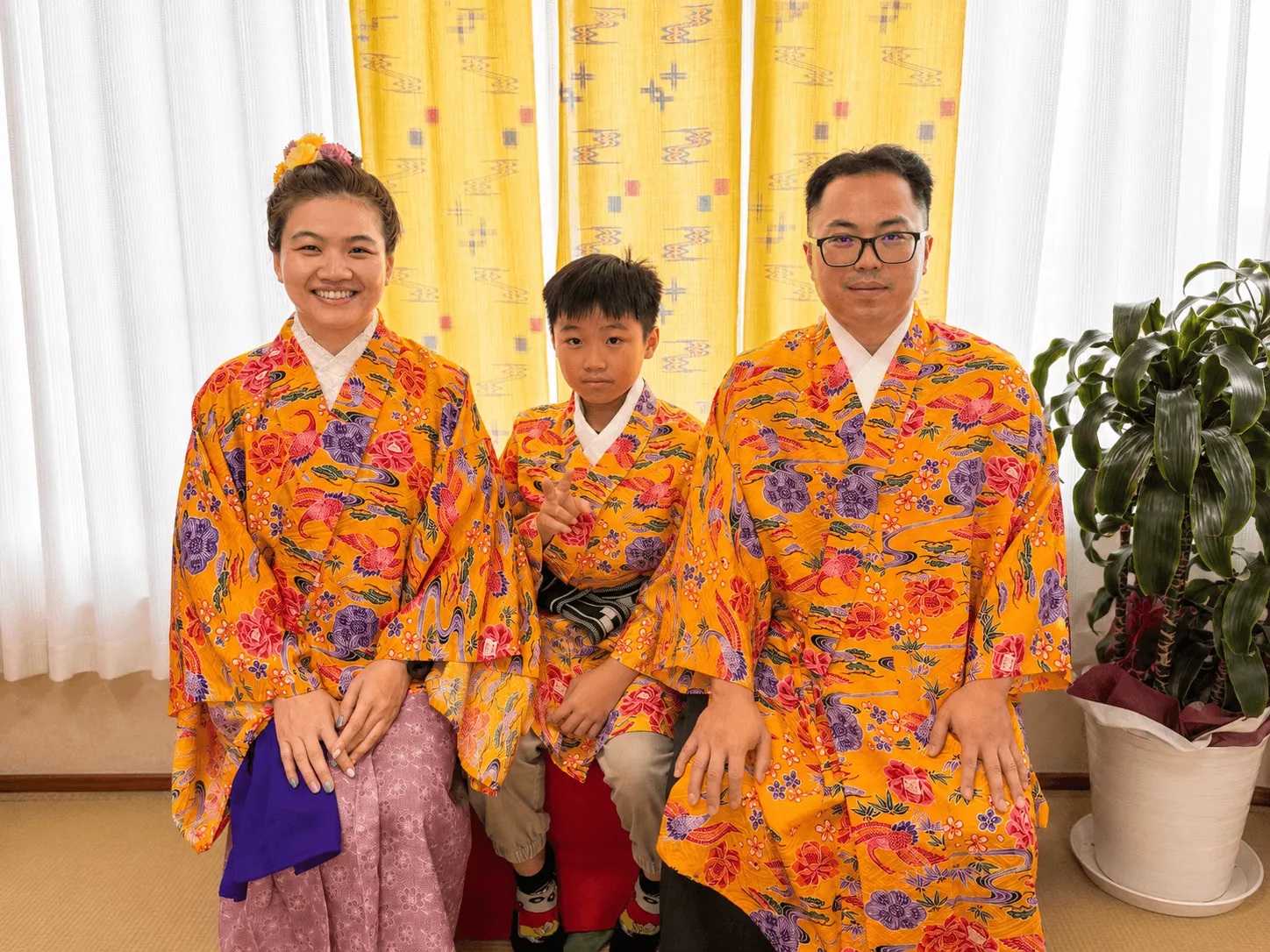 柄物の琉装を着用してポーズをとる父親と子どもたちの記念写真