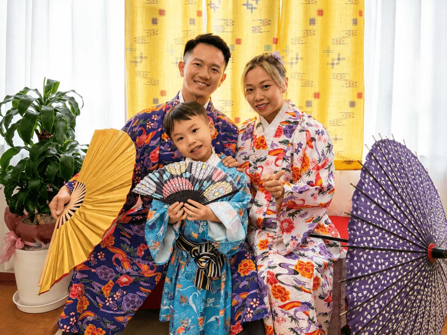 傘や扇子などの小物を手にして家族で記念撮影をする琉装体験写真