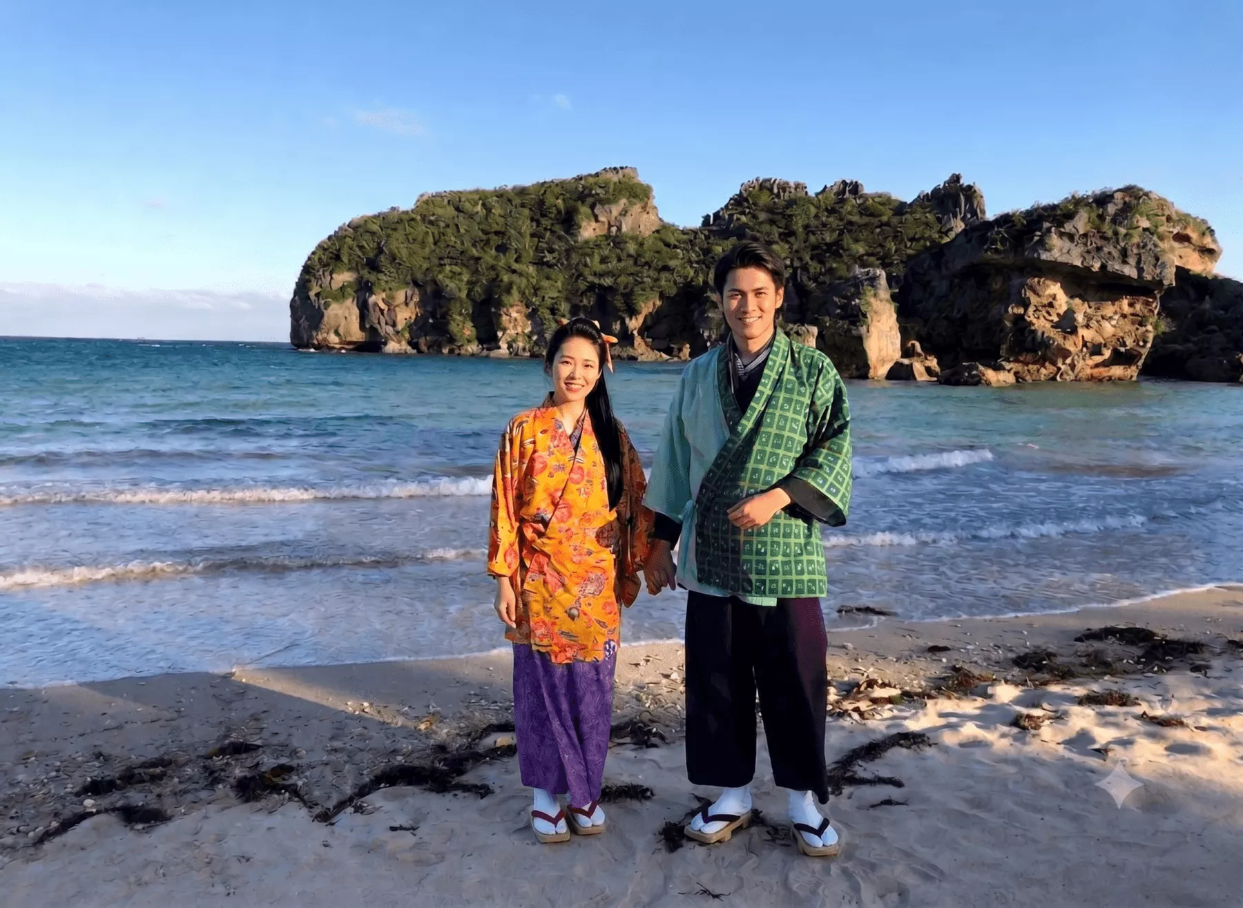 沖縄の美しいビーチを背景に琉装を着て立つ男女のロケーション写真