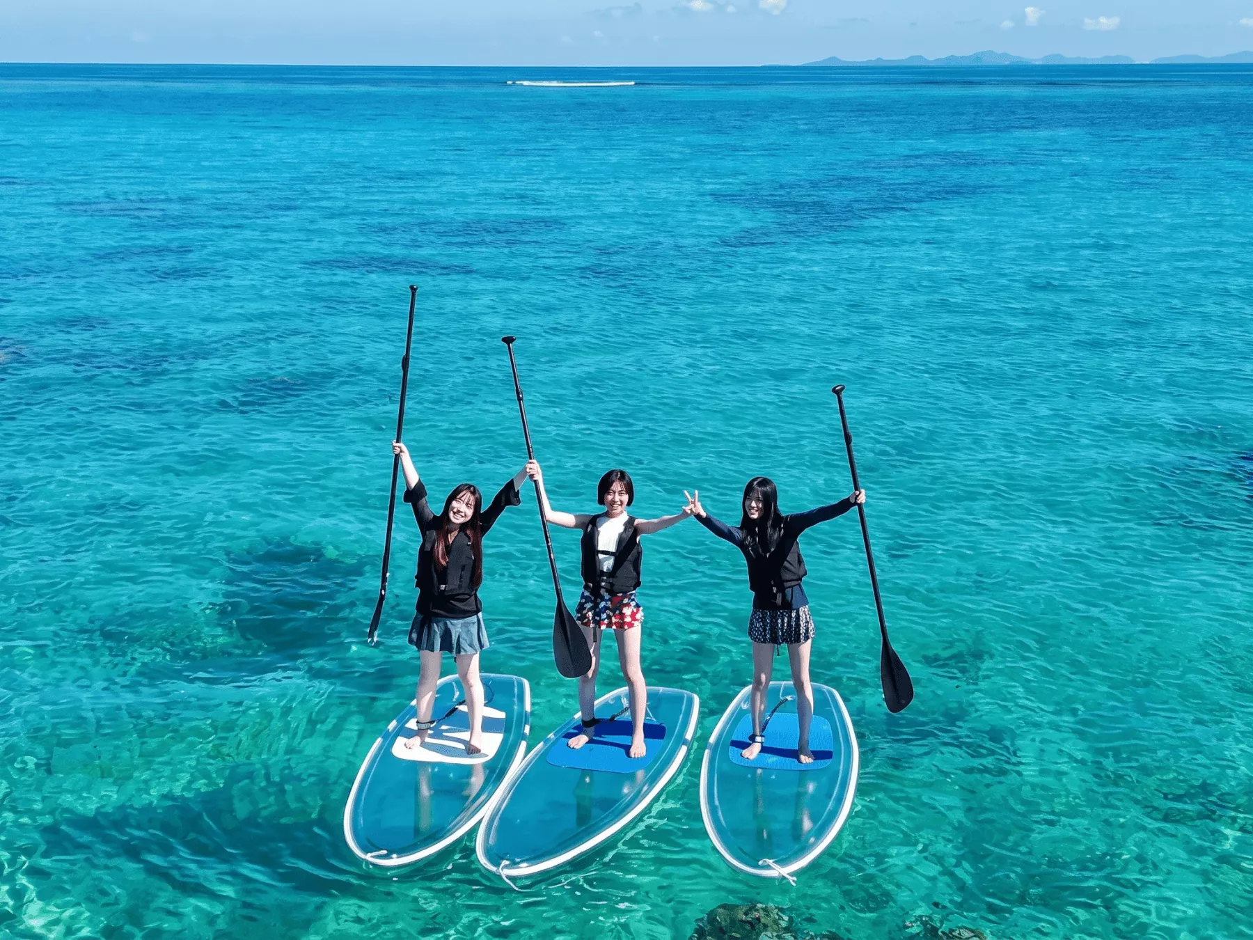 沖縄のエメラルドグリーンの海でパドルボード（SUP）ツアーを満喫する風景