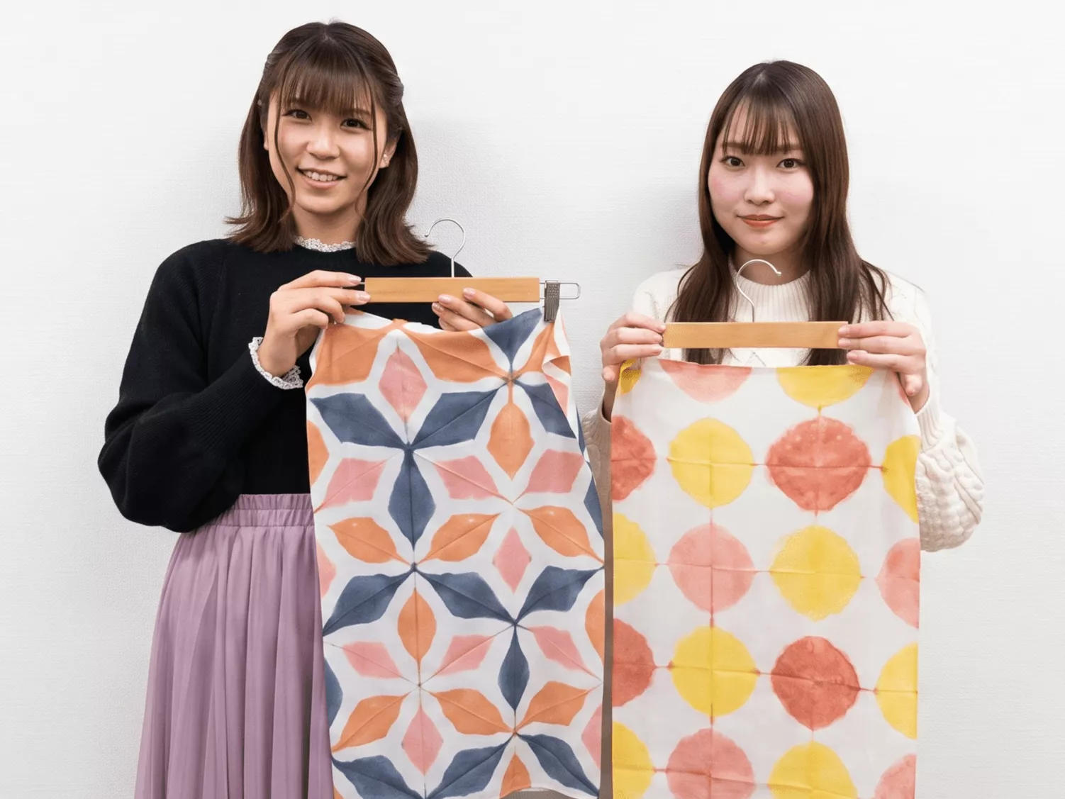 鮮やかな伝統模様に染め上がった手ぬぐい・風呂敷を広げて見せる女性たち