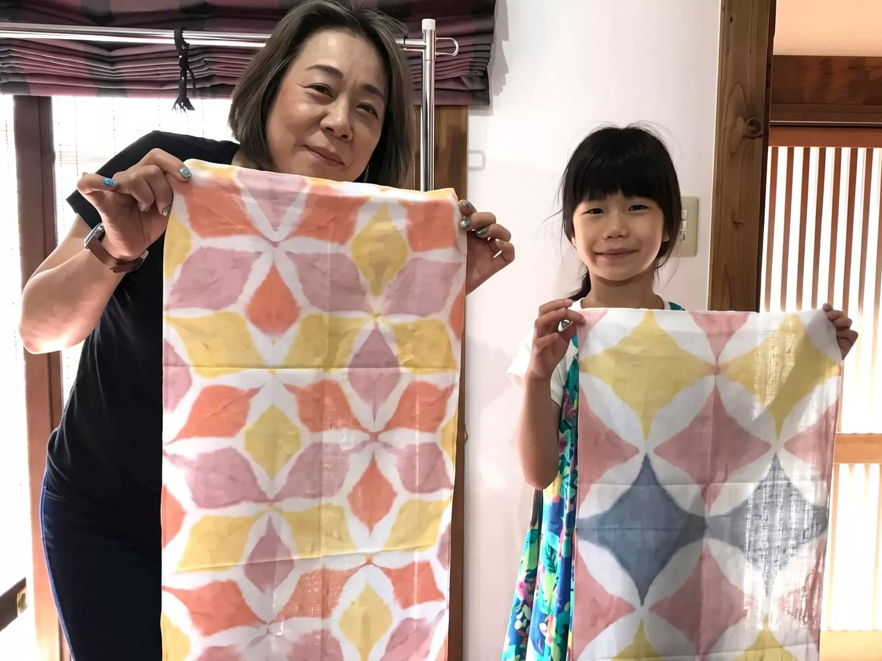 伝統的な模様に染め上がった手ぬぐい作品を披露する染色体験の参加者