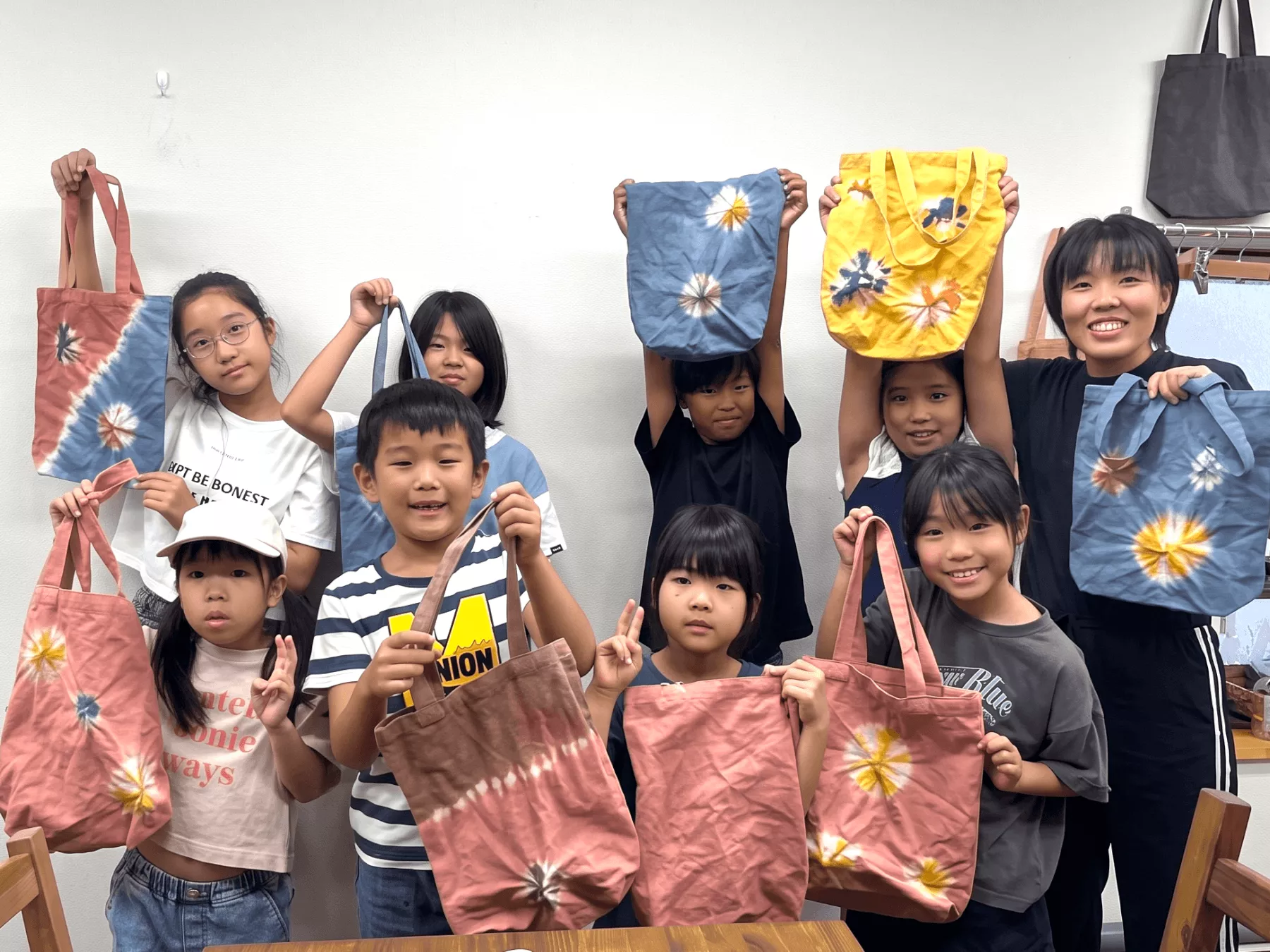 染め屋貴久の染色体験で完成したオリジナルのトートバッグを笑顔で見せる子供たち